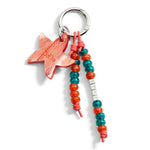 Load image into Gallery viewer, Charm a forma di stellina in bioresina arancione tangerine con dettagli in plastica riciclata e acciaio, appeso a una borsa.

