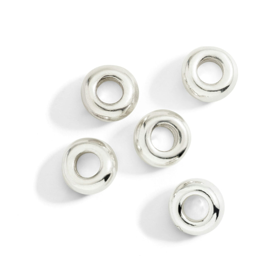Set di cinque componenti rondelle bold in argento 925, dettaglio della superficie lucida e riflettente.